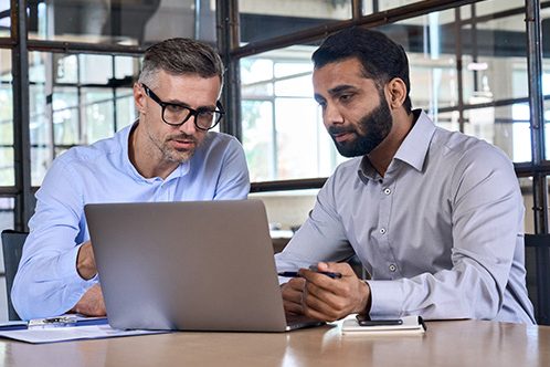 Kaksi miestä katsomassa kannettavan tietokoneen näyttöä